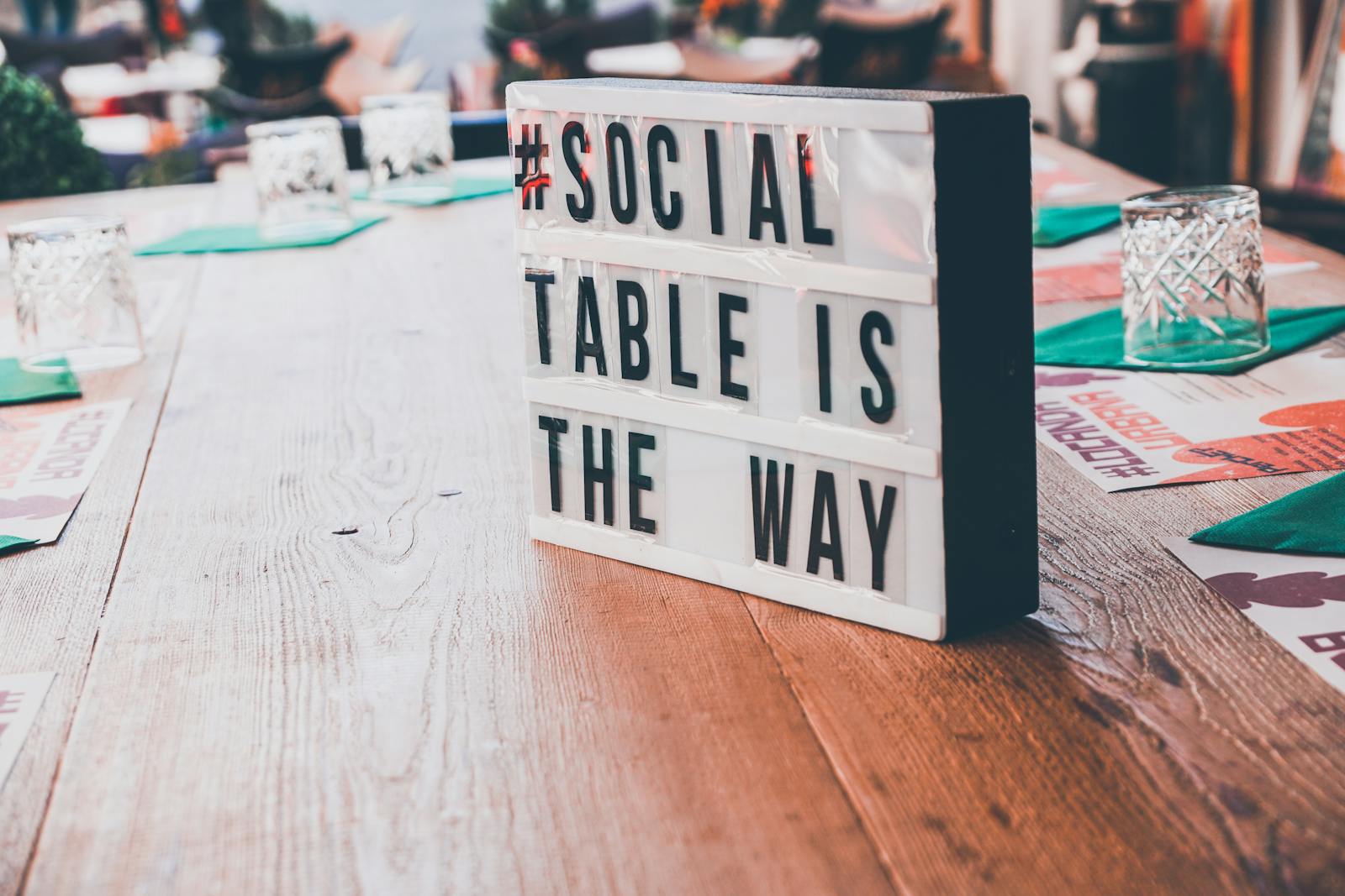 Close-up of social message sign on a wooden table outdoors.