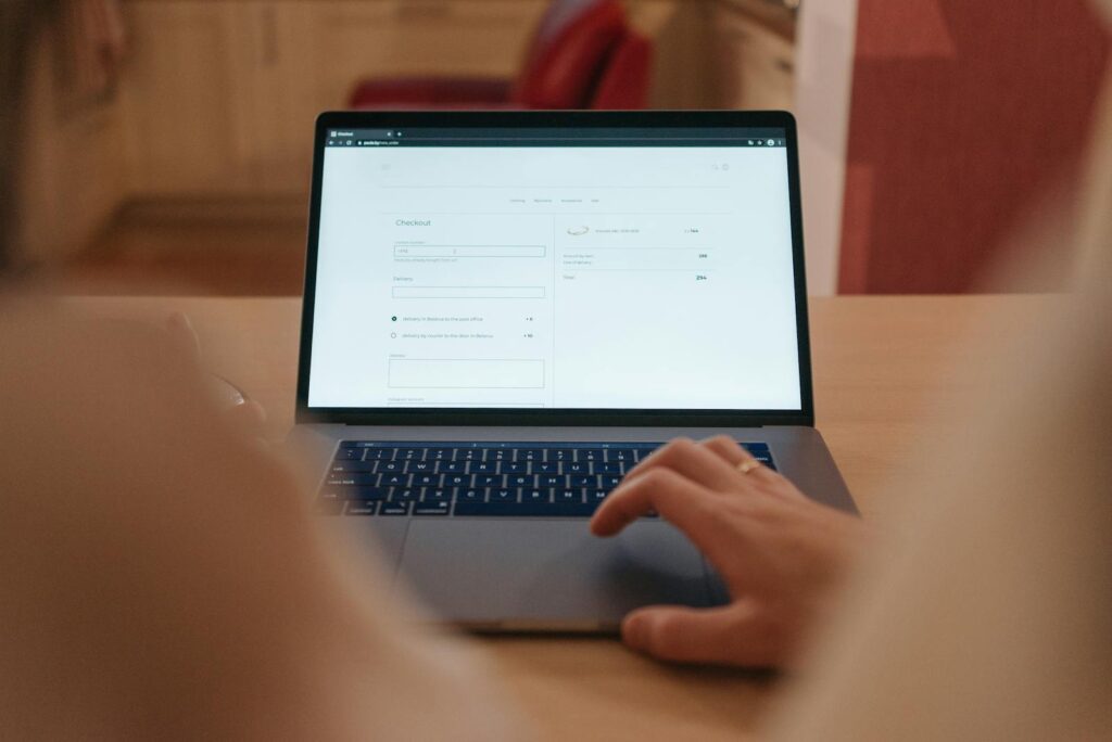 Close-up of a person navigating online checkout on a laptop screen in a cozy indoor setting.